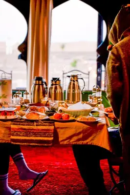 a table with food on it with people sitting at it at Merzouga White Camp - Official Luxury Camp in Merzouga
