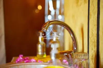 a bathroom sink with a faucet and a bottle of soap at Merzouga White Camp - Official Luxury Camp in Merzouga