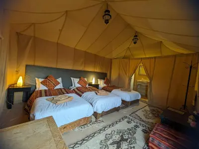 a bedroom with three beds in a tent at Erg Chebbi Romantic Desert Camp in Merzouga