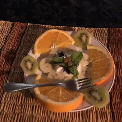 a plate of fruit on a table with a fork at Erg Chebbi Romantic Desert Camp in Merzouga