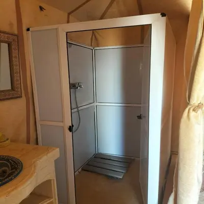a shower stall with a glass door in a room at Erg Chebbi Romantic Desert Camp in Merzouga