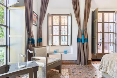 a bedroom with a bed and a desk and windows at Villa Pauline with private pool & jacuzzi, hotel service and no insight in Marrakech