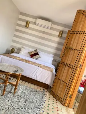 a bedroom with a bed with a striped wall at Riad Fes Colors & SPA - Family Lodging in Fès