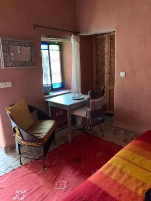 a bedroom with a table and chairs in a room at RIAD CHANT D'ETOILES tadighoust in El Hara