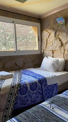 two beds in a room with two windows at Auberge IMIN TAGHYA in Akhendachou nʼAït Ouffi