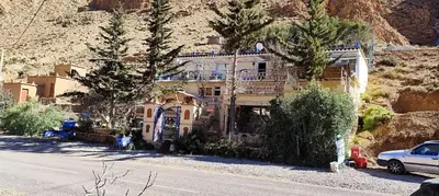 a house on the side of a mountain with a car parked in front at Auberge IMIN TAGHYA in Akhendachou nʼAït Ouffi