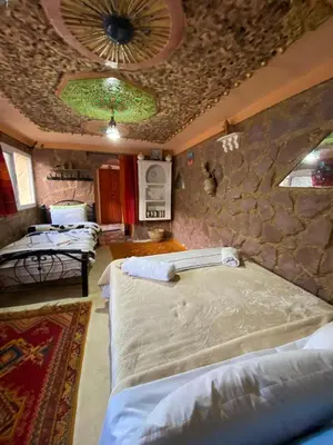 a bedroom with three beds and a stone wall at Auberge IMIN TAGHYA in Akhendachou nʼAït Ouffi