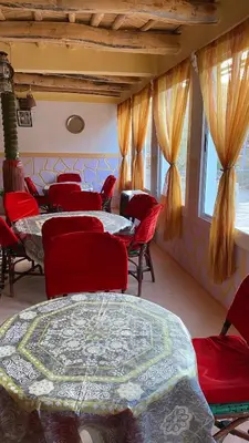 a dining room with tables and chairs and windows at Auberge IMIN TAGHYA in Akhendachou nʼAït Ouffi