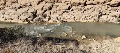 a body of water next to a rocky cliff at Auberge IMIN TAGHYA in Akhendachou nʼAït Ouffi