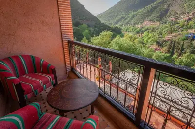 a balcony with a table and chairs and a view at Dar Ikalimo Ourika in Aghbalou