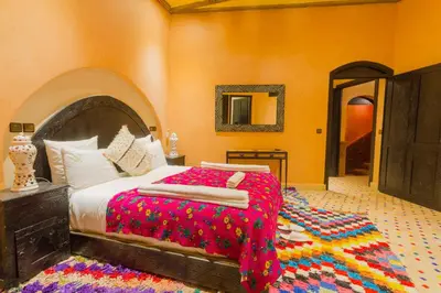 a bedroom with a large bed with a colorful blanket at Dar Ikalimo Ourika in Aghbalou