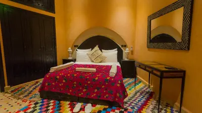 a bedroom with a bed with a red blanket at Dar Ikalimo Ourika in Aghbalou