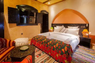 a bedroom with a large bed and a couch at Dar Ikalimo Ourika in Aghbalou
