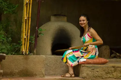 a woman in a colorful dress sitting on a wall with an oven at Dar Ikalimo Ourika in Aghbalou
