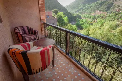 a balcony with two chairs and a table and a view at Dar Ikalimo Ourika in Aghbalou