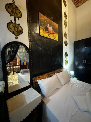 a bedroom with a white bed and a mirror at Riad Abqari Youssefi in Fès