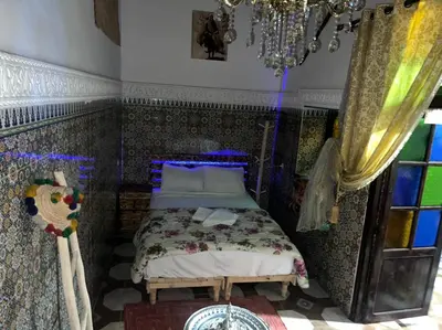 a bedroom with a bed and a chandelier at Riad Abqari Youssefi in Fès