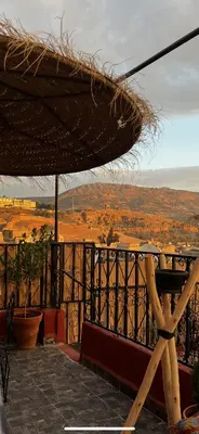 a large straw umbrella on a balcony with a view at Riad Abqari Youssefi in Fès
