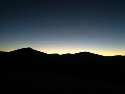 a silhouette of mountains with the sunset in the background at AUBERGE KACHTi in Mhamid