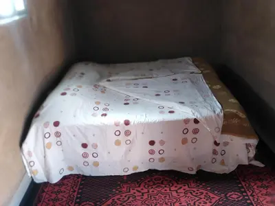 a small bed in a corner of a room at AUBERGE KACHTi in Mhamid