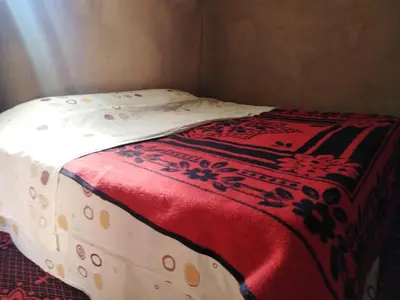 a bed with a red and white blanket on it at AUBERGE KACHTi in Mhamid