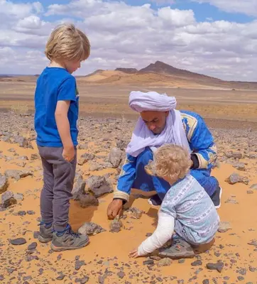 a woman and two children playing in the desert at Authentic Luxury Camp in Merzouga