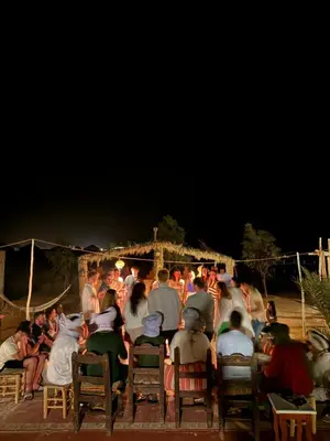 a crowd of people sitting in chairs at night at Authentic Luxury Camp in Merzouga