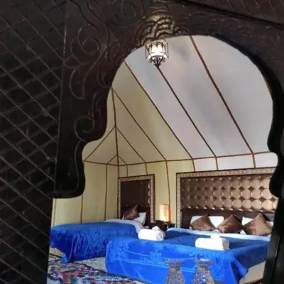 a room with two beds and a large mirror at Authentic Luxury Camp in Merzouga