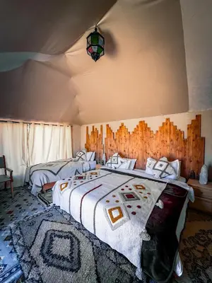 a bedroom with a large bed with a comforter at Authentic Luxury Camp in Merzouga