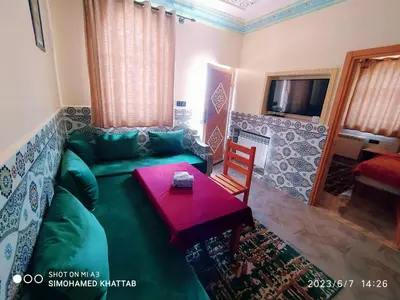 a living room with a green couch and a table at Chalets ITO Atlas Timnay in Midelt