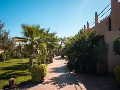 a pathway with palm trees and a building at Maison Daouia in Marrakech