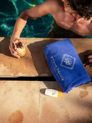 a man holding a donut on a table next to a pool at Maison Daouia in Marrakech