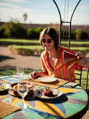 a woman sitting at a table drinking from a pitcher at Maison Daouia in Marrakech