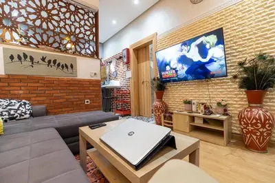 a living room with a couch and a tv on a brick wall at FIFI maison in Ouarzazate