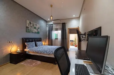 a bedroom with a bed and a desk with a computer at FIFI maison in Ouarzazate