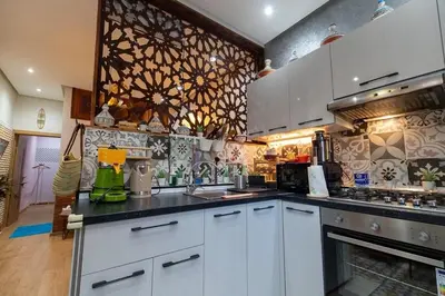a kitchen with white cabinets and black counter tops at FIFI maison in Ouarzazate