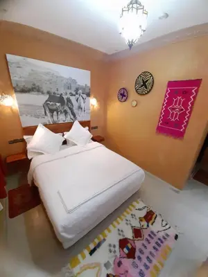 a bedroom with a large white bed and a rug at Riad ait Ben Haddou in Aït Ben Haddou