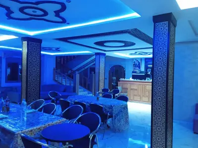a dining room with blue lighting and tables and chairs at Relais Des Nomades in Tinerhir