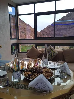 a table with a bowl of food and bottles of wine at Relais Des Nomades in Tinerhir