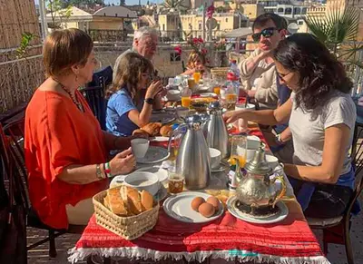a group of people sitting at a table eating food at Dar Lmrama Fes - Entire Guest House in Fès