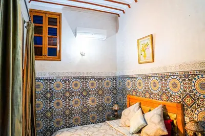 a bedroom with a bed with blue and gold wallpaper at Dar Lmrama Fes - Entire Guest House in Fès