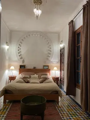 a bedroom with a large bed and a chandelier at DAR SEFFAH au cœur de la Médina in Fès
