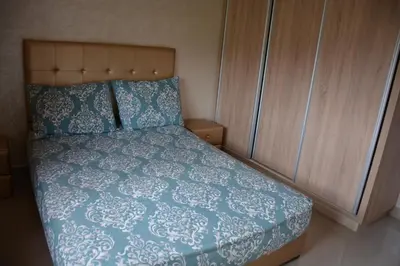a bedroom with a bed with a blue comforter and wooden cabinets at Ozoud high standing appartment in Ouzoud