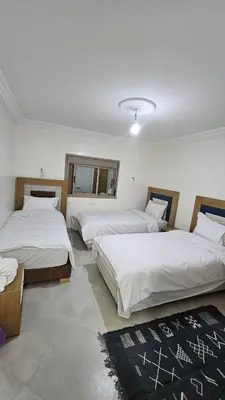 a bedroom with two beds and a rug at ESPACE INOV IMILCHIL in Imilchil