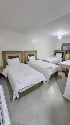 three beds in a room with white sheets at ESPACE INOV IMILCHIL in Imilchil