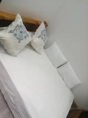 a bed with white sheets and two pillows at Bab aissi home in Meknès