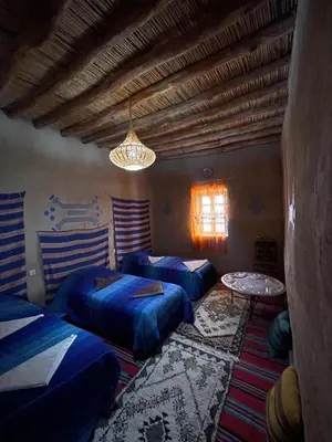 a room with two beds and a table in it at Dar Oasis Moringa in Merzane