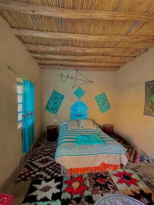 a bedroom with a bed and a wooden ceiling at Dar Oasis Moringa in Merzane