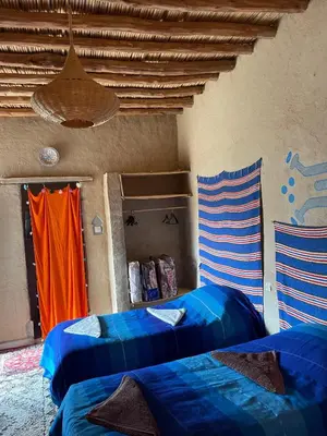 a room with two beds and an orange curtain at Dar Oasis Moringa in Merzane