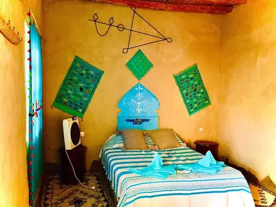a bedroom with a bed with a blue head board at Dar Oasis Moringa in Merzane